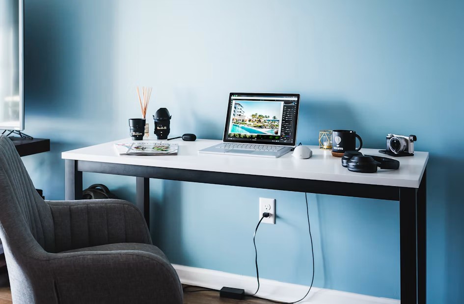 Minimalistischer Schreibtisch mit Bauplänen und Laptop.